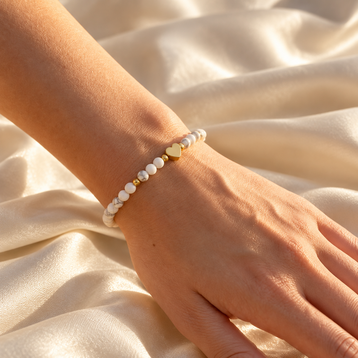 Gros plan du bracelet Amélia Cœur blanc sur un poignet, ambiance ivoire Elvyora