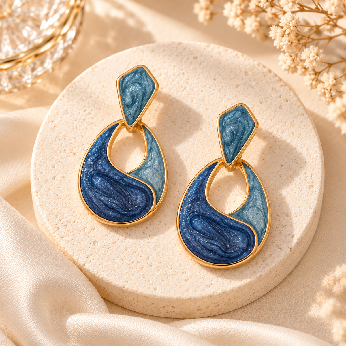 Boucles Maélys dorées et bleues présentées sur socle clair