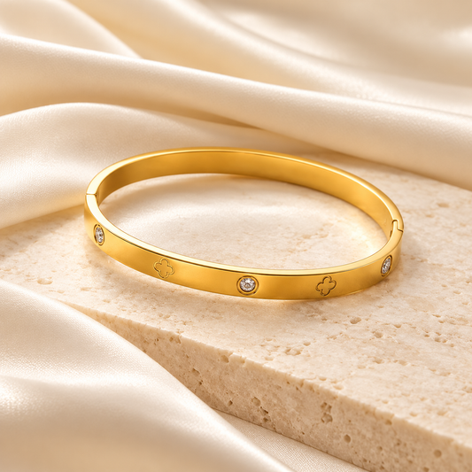 Bracelet jonc Céliane doré, trèfles gravés et détails scintillants sur fond ivoire